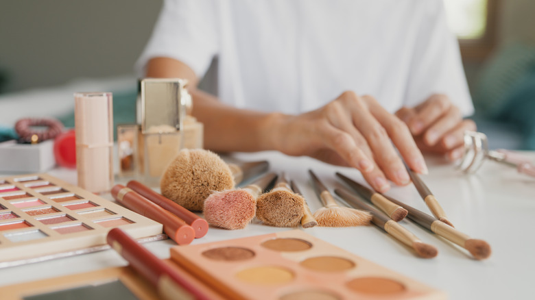 Person sorting out cosmetics and makeup brushes