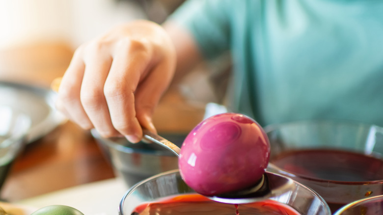 A person dyes eggshells bright colors