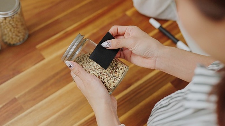 Person holding a spice jar by a wooden countertop