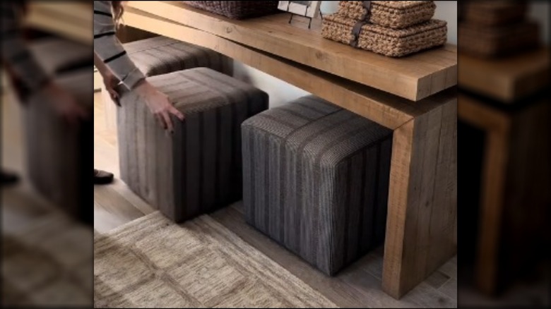 Hands tucking ottoman away under table
