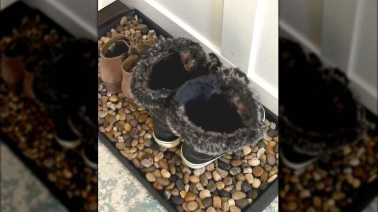 Boot tray filled with river rocks and two pairs of boots on it