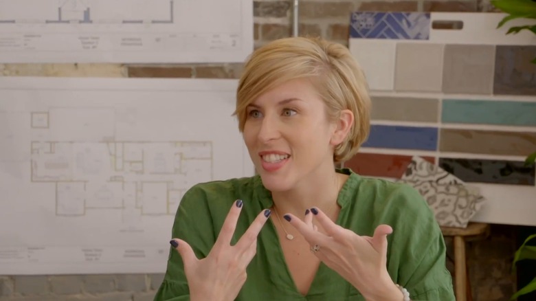 Erin Napier sitting with color swatches and floor plans behind her