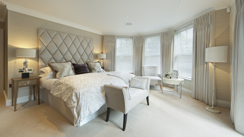 A bedroom with large windows covered with curtains and blinds