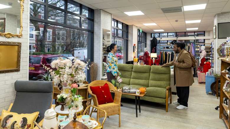 Pair of shoppers in a thrift store looking at furniture
