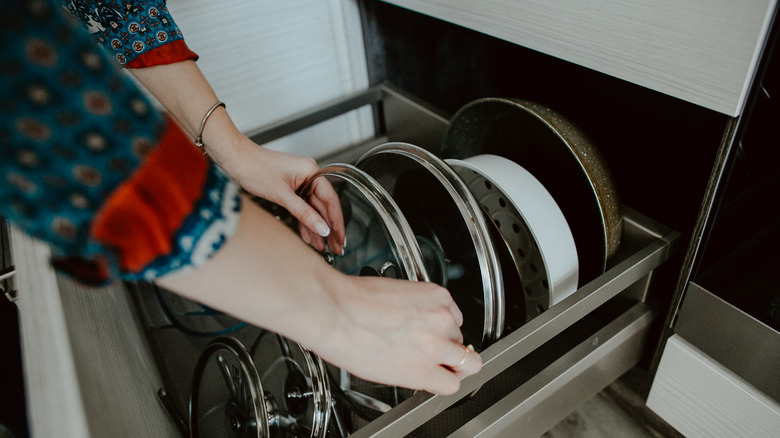 Woman grabbing a pot lid from her organized collection
