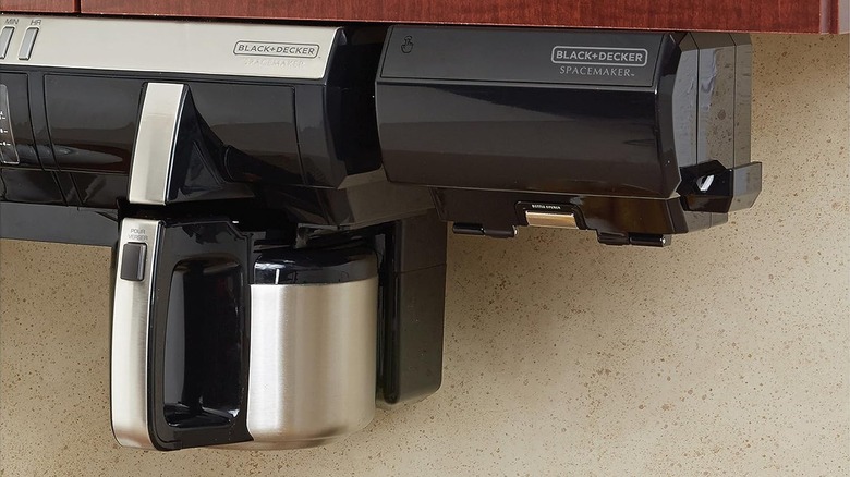 A Black and Decker electric can opener is mounted under a wood cabinet