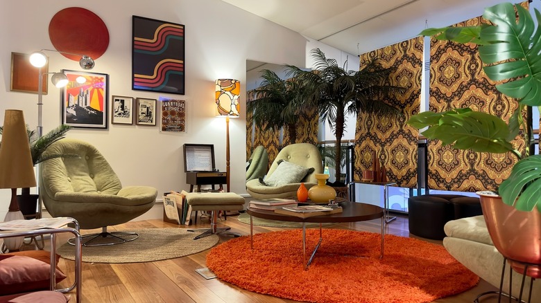 A 70s inspired living room with wall decor, modular furniture, an orange shag rug, and indoor plants