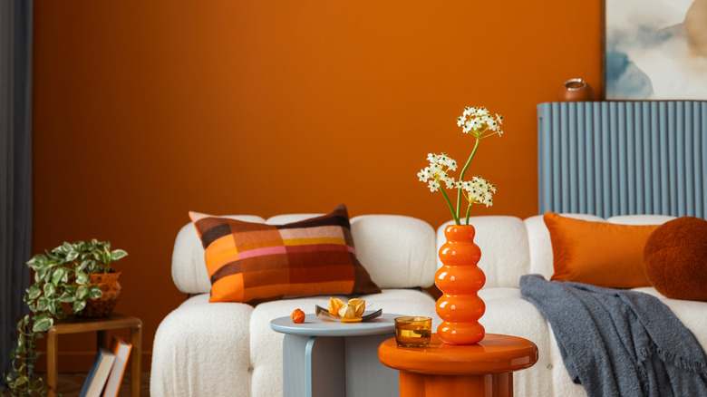 A 70s-inspired living room with orange walls, a white modular sofa, and retro accents