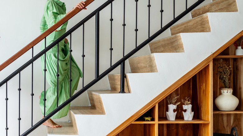 Woman in green dress walking up staircase