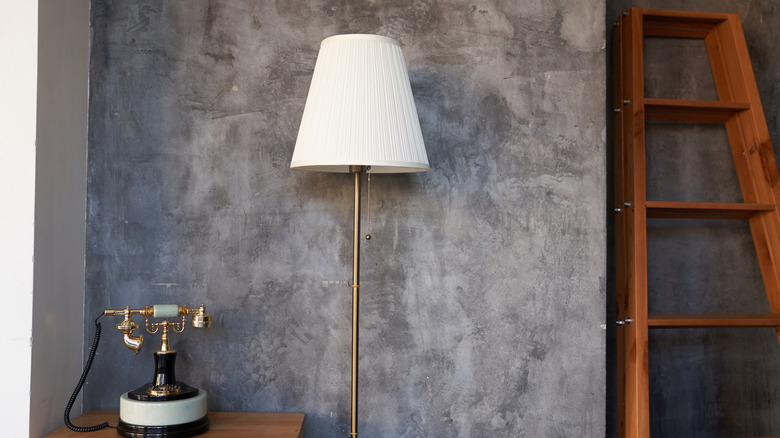 Old floor lamp, antique phone, and a ladder in a room