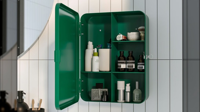 A variety of bath products are shown on the shelves of an emerald green wall cabinet