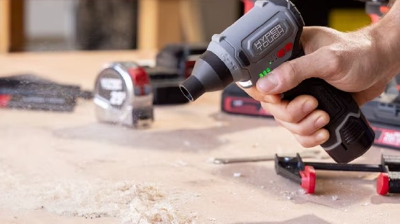 Hand holding a small cordless blower over a workbench