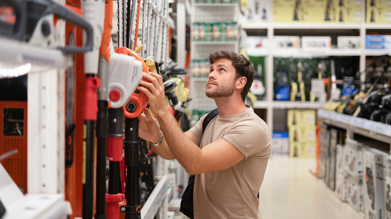 Young man shopping in outdoor tools section in a store