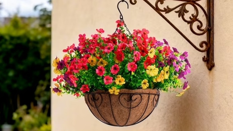 A hanging flower basket is hanging from an outdoor post