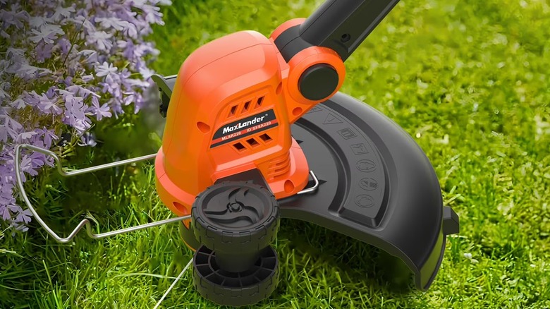 A black and orange weed wacker being used in a lawn