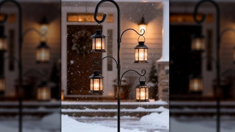 A tall, black shepherd's hook with lanterns hanging on it