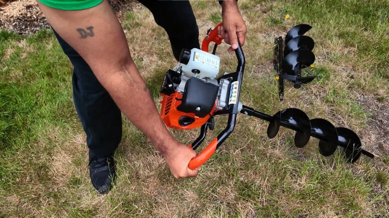 Man holding a prowoo auger post hole digger in the yard