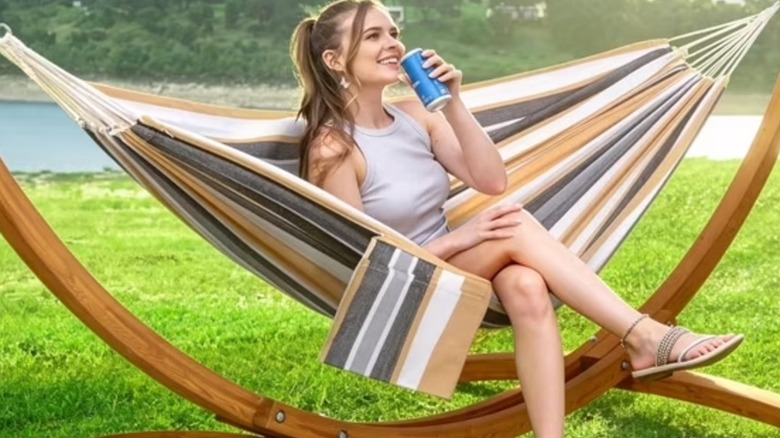 A woman sitting on a hammock and sipping a drink