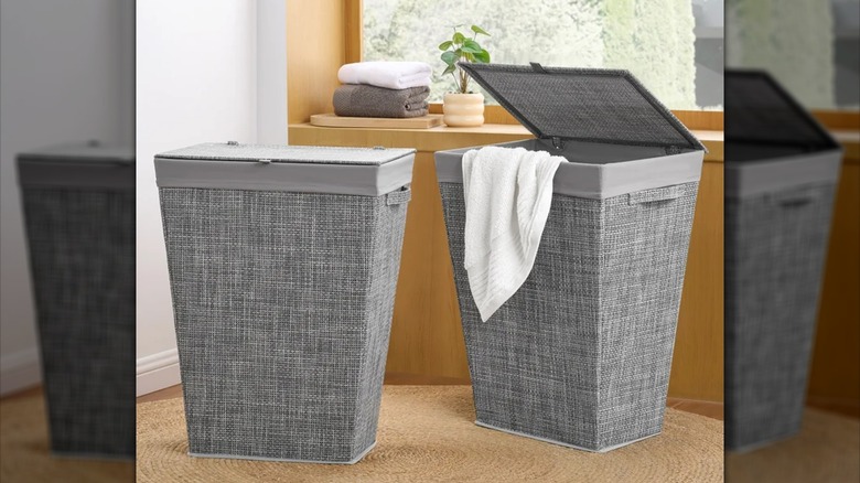 Two gray laundry hampers sit next to each other in a neutral room