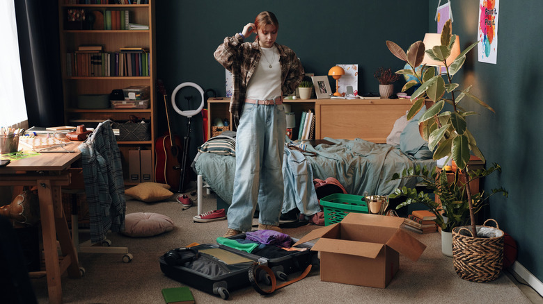 A young woman stands in a messy room that needs organization