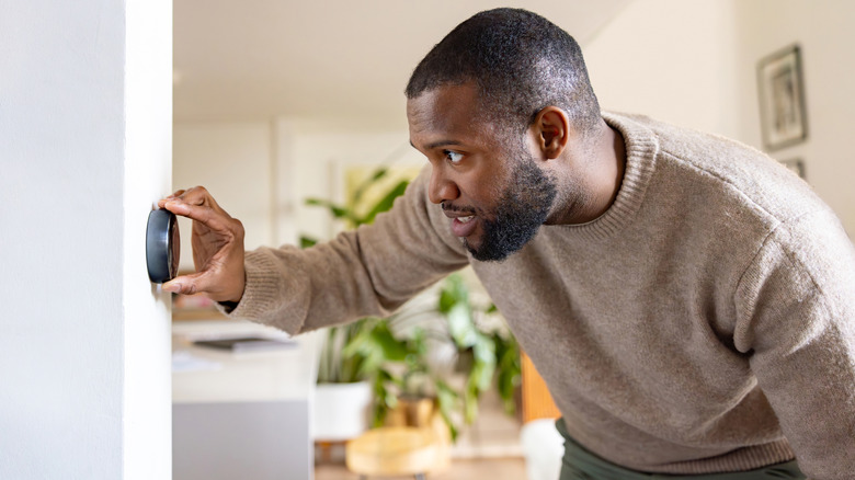 person adjusting digital thermostat on wall