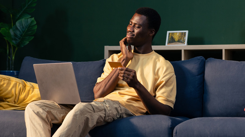 A man holds a card, thinking