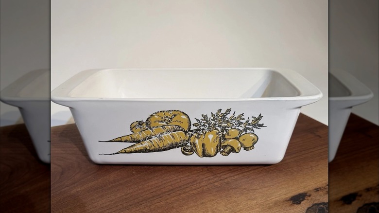 A vintage Nature's Bounty pattern CorningWare dish with mustard yellow vegetables on white glass.