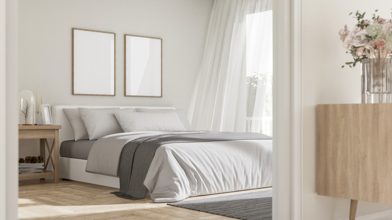 A modern contemporary bedroom with flat white walls and gray bedding
