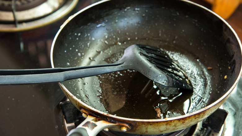 spatula in pan filled with used cooking oil from frying