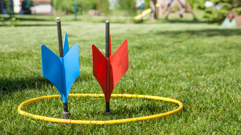 Lawn darts stuck in a yard target hoop