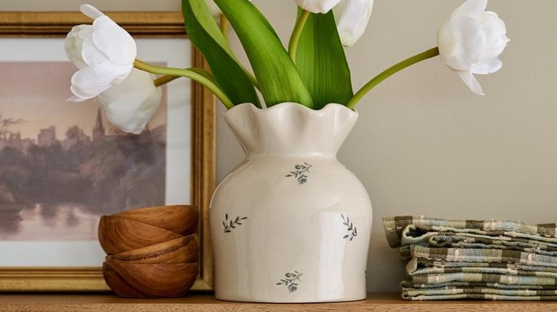 A delicate ceramic floral vase is filled with white silk tulips