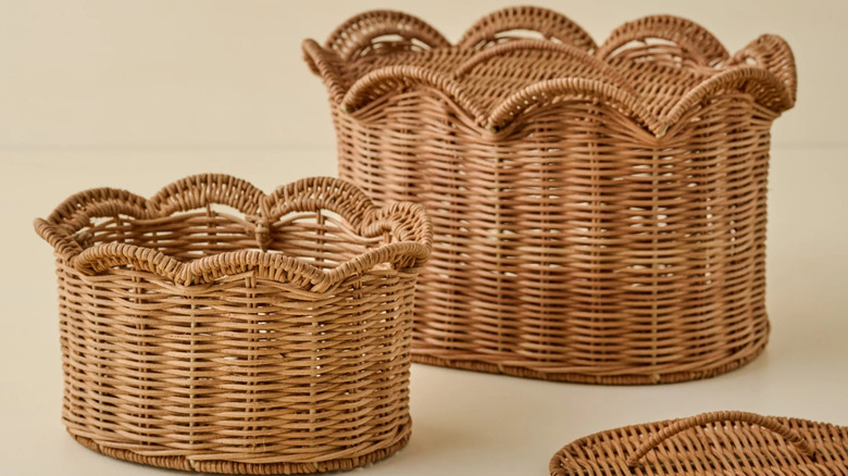 Two scalloped woven baskets sit on a cream-colored table