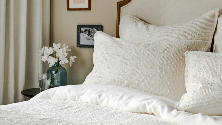 An elegant bed is dressed with creamy white vintage chenille shams