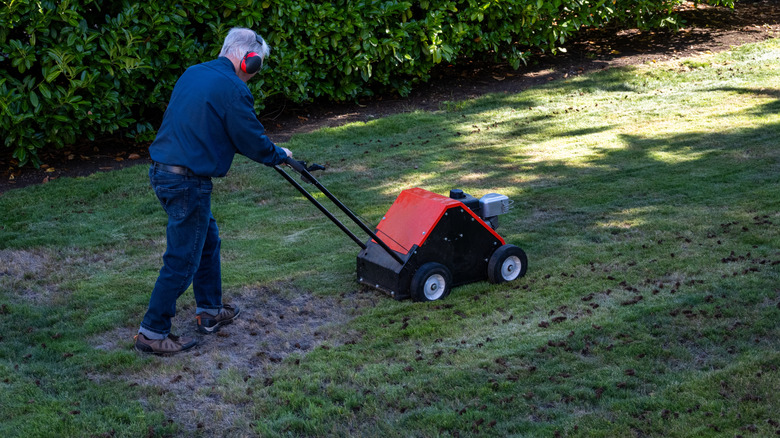man aerating a lawn with a self-propelled core aerator