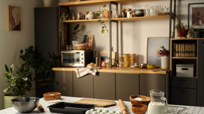 Kitchen table with baking supplies and appliances on open shelf in background
