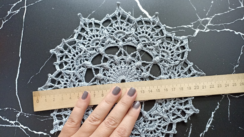 hand measuring doily with ruler
