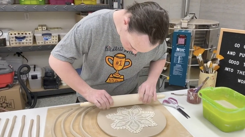 person rolling doily into clay