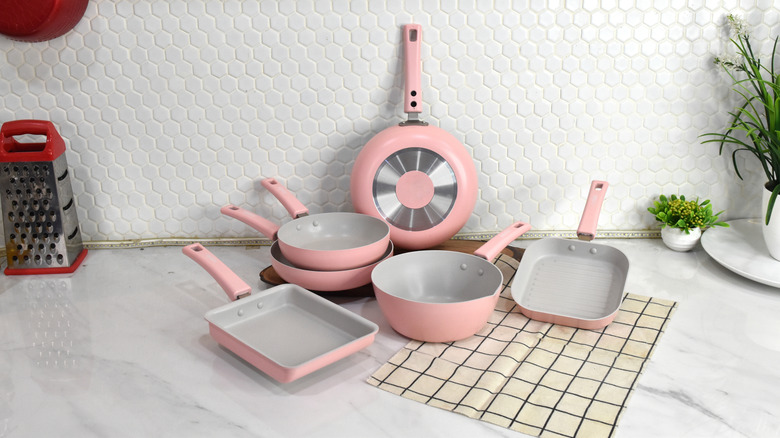 Pink pots and pans in a neutral-toned kitchen on a marble counter