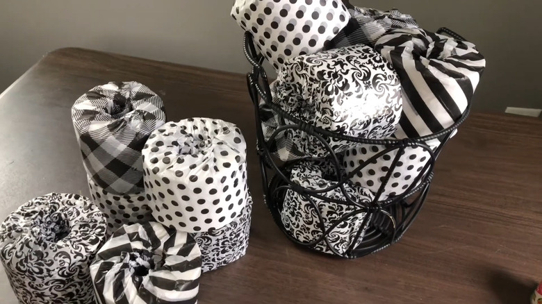 Several rolls if toilet paper wrapped in black and white tissue paper