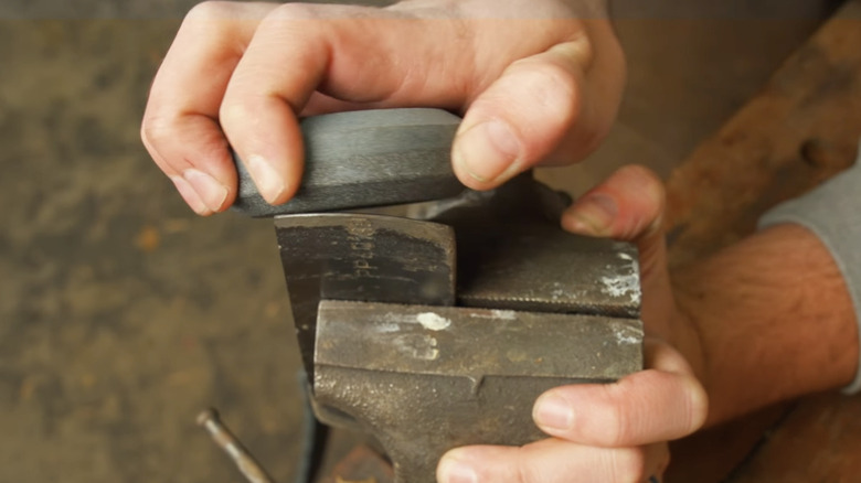 a man sharpens a lawn mower blade with a sharpening puck