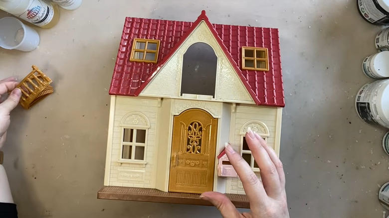 Person upcycling a plastic dollhouse
