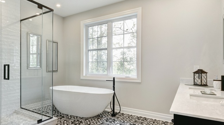 Modern bathroom with glass shower and window next to bathtub