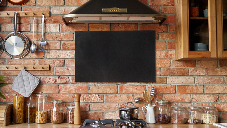 A kitchen with an exposed red brick wall