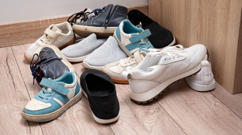 A pile of assorted shoes on a wooden floor