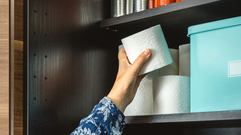 Person stacking toilet paper in a cabinet