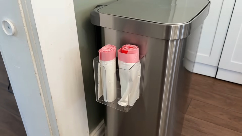 Trash bags sitting in plastic dryer sheet holder attached to tall metal trash can in kitchen corner