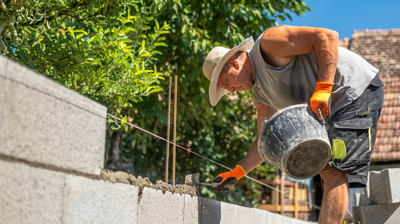 A man building a retaining wall made of concrete blocks