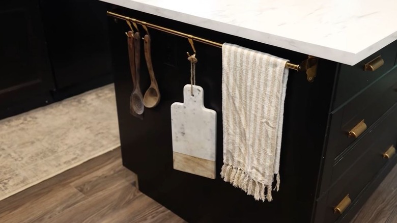 An IKEA HULTARP Rail hung on a kitchen island with kitchen utensils and supplies hanging off of it