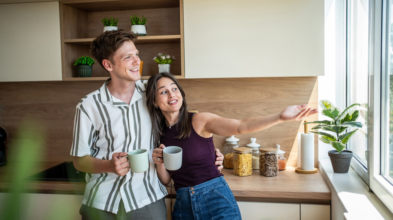 A couple smiling and looking at the kitchen window