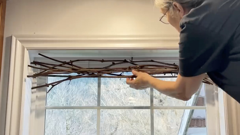 woman hanging branches in window